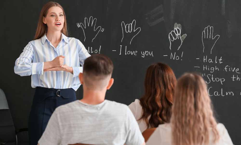 Image of Woman teaching ASL class in front of a blackboard